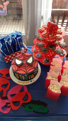 a spiderman themed cake and cupcakes on a table