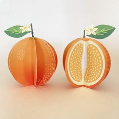 an orange cut in half sitting on top of a white table next to another piece of fruit