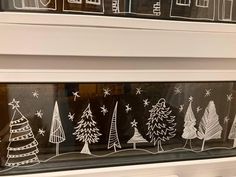 the window is decorated with christmas trees and snowflakes in black and white ink