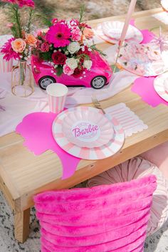 a table set up with pink and white plates, cups, napkins and flowers