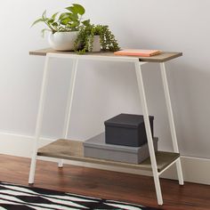 a small table with a plant on it next to a black and white area rug