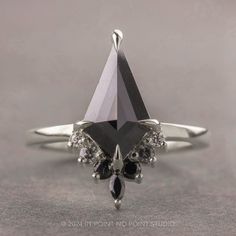 a black and white diamond ring sitting on top of a gray surface with diamonds around it