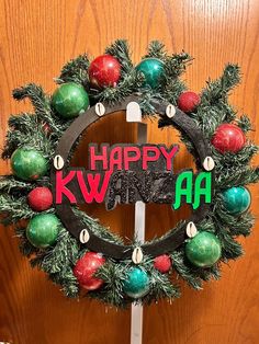 a wreath with the words happy kwan on it and ornaments hanging from it's sides