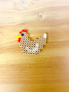 a chicken brooch sitting on top of a wooden table