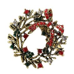 a red and green broochle with leaves on the front, surrounded by small crystal stones