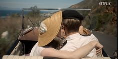 a man and woman kissing in the back of an old fashioned car on a road