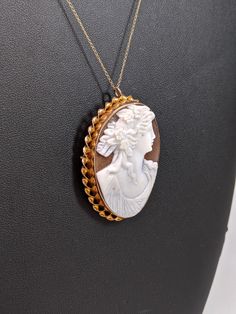 This piece is made of 10k yellow gold. The cameo is bezel set and has a twisted gold halo. The cameo is both a pendant and a brooch. The cameo is 47x33mm. Originally $800, but is now on sale for $550. (Chain not included, but can be provided upon additional purchase) Fine Yellow Gold Cameo Jewelry, Yellow Gold Cameo Jewelry For Wedding, Formal Yellow Gold Cameo Jewelry, Classic Yellow Gold Cameo Jewelry, Cameo 14k Gold Round Jewelry, 14k Gold Cameo Round Jewelry, 14k Gold Cameo Jewelry, Antique 14k Gold White Jewelry, White Oval Brooch Jewelry