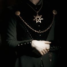 a woman wearing a black dress and holding a star on her chest, in the dark