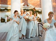 a group of women standing next to each other in front of a building holding bouquets