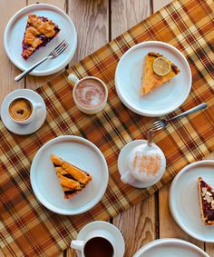 there are many different desserts on the table with cups and saucers next to each other