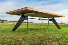 a wooden table sitting on top of a lush green field