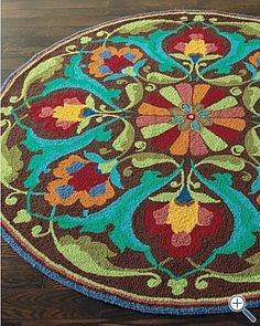 a round rug with an ornate design on the center and sides in multicolors