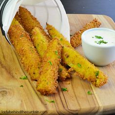 some fried food is on a cutting board next to a small white bowl and dipping sauce