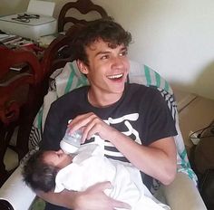 a young man holding a baby in his arms