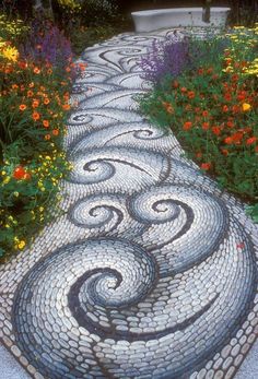 a garden path made out of cobblestones with flowers in the backround