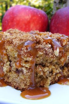 a close up of a piece of cake on a plate with apples in the background