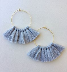 a pair of blue tasselled hoop earrings on a white surface with gold rims