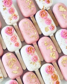 pink and gold decorated marshmallows are arranged on wooden skewers with flowers