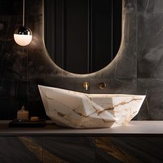 a marble sink in front of a round mirror with lights on the wall behind it