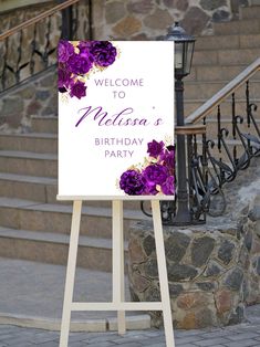 a welcome sign with purple flowers on it in front of some steps and railings