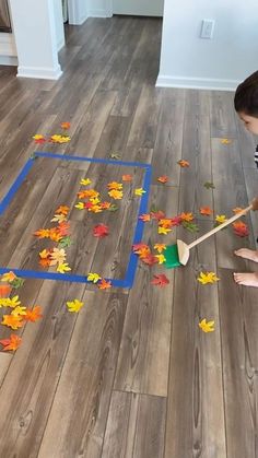 a young boy is playing with leaves on the floor