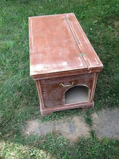 an old wooden box sitting in the grass with its door open to reveal a dog's house