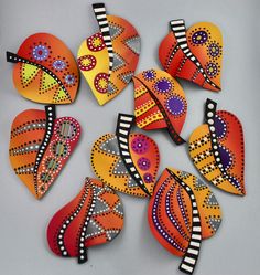 a group of orange and black heart shaped brooches on a gray surface with white stripes