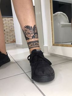 a woman's legs with tattoos and sneakers on the floor in front of a mirror