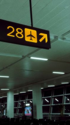 an airport sign hanging from the ceiling in front of windows