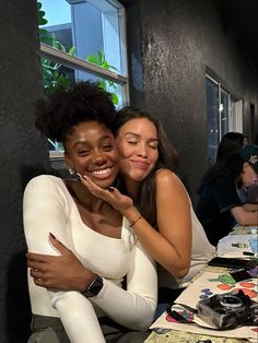 two women sitting next to each other at a table