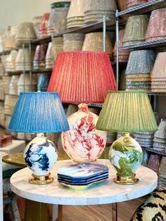 three lamps sitting on top of a table in front of a wall of vases