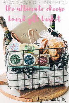 a basket filled with cheese and wine on top of a wooden table next to a sign that says, the ultimate cheese board gift basket