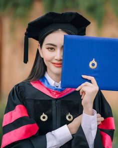 a woman in graduation gown holding up a laptop