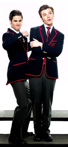 two men in suits standing next to each other with their hands on their hipss