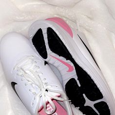 a pair of white and pink nike shoes on a bed covered in fur, taken from above