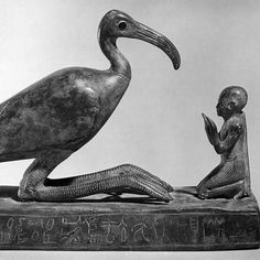 an egyptian statue with a pelican sitting on it's lap and another bird standing next to it