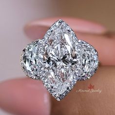 a close up view of a diamond ring on someone's hand, with the center stone surrounded by diamonds