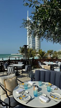 an outdoor dining area with tables and chairs overlooking the ocean in front of a tall building