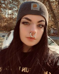 a woman with fake nose piercings on her nose and nose ring in front of a car