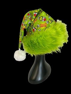 the grin hat is on top of a mannequin's head and has green fur