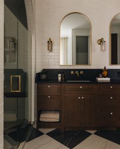 a bathroom with two sinks and mirrors on the wall next to a walk in shower