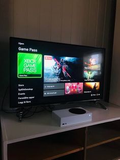 a large flat screen tv sitting on top of a white table next to a wall