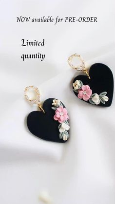 two black heart shaped earrings with pink flowers on the front and white petals on the back