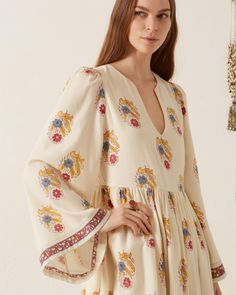 Crafted from wool, our floral motif dress has graceful bell sleeves, a V-neckline, and a gathered skirt. The long dress is hand-block printed with falling blooms and border-print cuffs. Pair it with a pair of cowboy boots for a western-inspired look. This textile was block-printed by hand. Subtle printing and dye variations are part of the unique beauty of the garment and a signature of the artisan's hand. Bohemian Long Sleeve Dress With Gathered Sleeves, Bohemian V-neck Dresses With Gathered Sleeves, Bohemian Dresses With Elastic Sleeves, Folk Style Long Sleeve Floral Print Dress, Folk Style Long-sleeved Floral Print Dress, Bohemian Floral Print Dress With Bishop Sleeves, Bohemian Bell Sleeve Maxi Dress With Floral Print, Flowy Floral Print Dress With Bell Sleeves, Flowy Floral Print Bell Sleeve Dress