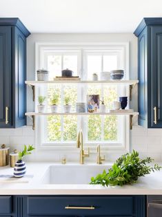 a kitchen with blue cabinets and white counter tops, gold faucets and brass pulls