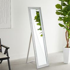 a large mirror sitting next to a potted plant on top of a white floor