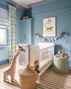 a baby's room with blue walls, striped rug and giraffe stuffed animal