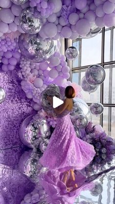 a woman in a purple dress is surrounded by balloons