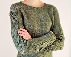 a woman is wearing a green sweater and has her arms crossed