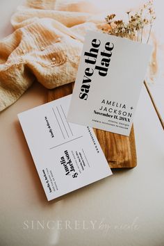 the save the date cards are next to some dried flowers on a wooden cutting board